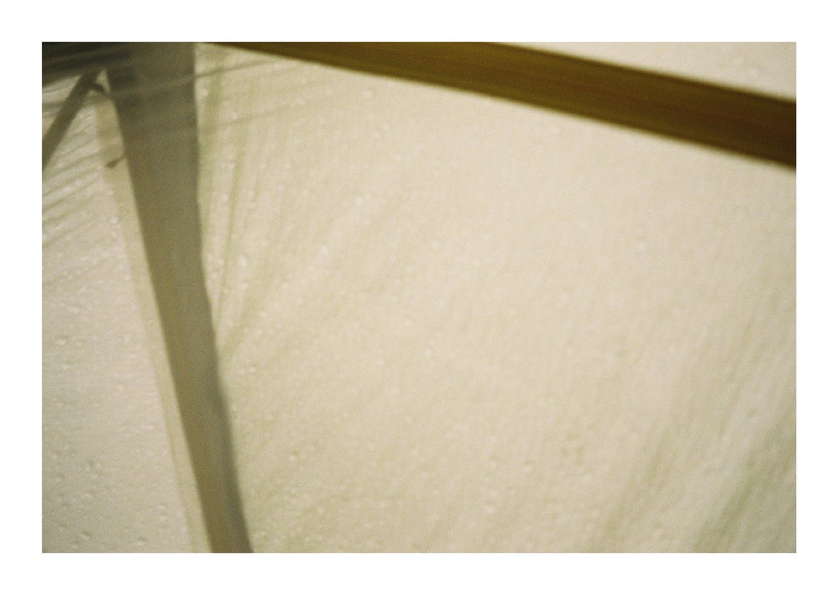 Rain beading on the pale fabric of a tent or tarp
