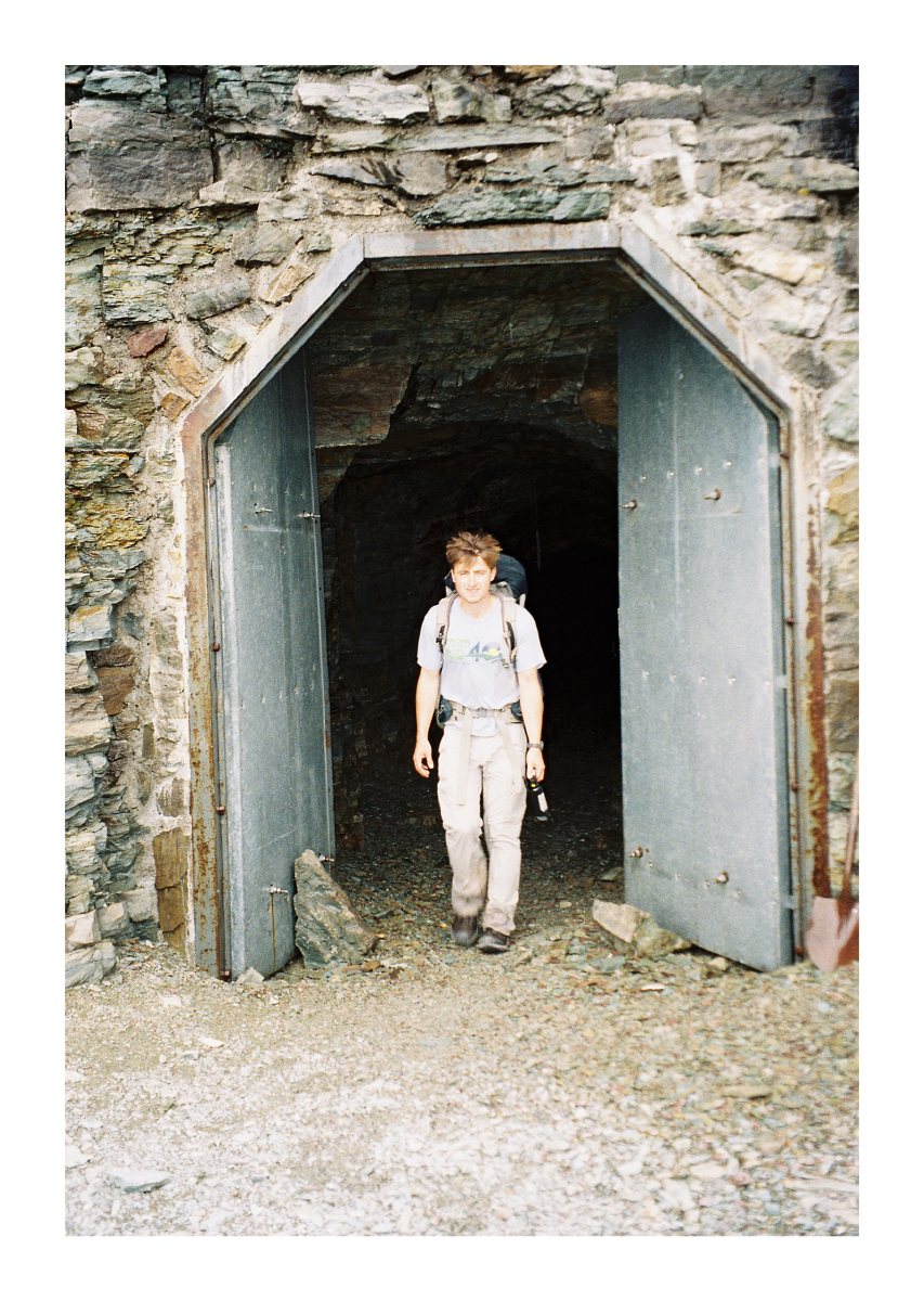 A backpacker emerging from the open doors of a stone tunnel