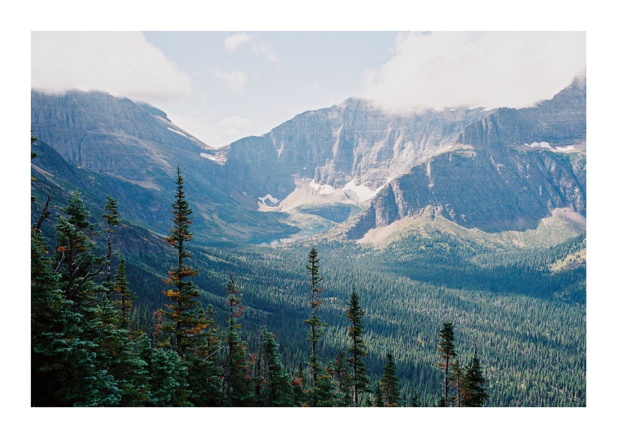 A broad mountain cirque with lingering snow above a dense evergreen valley