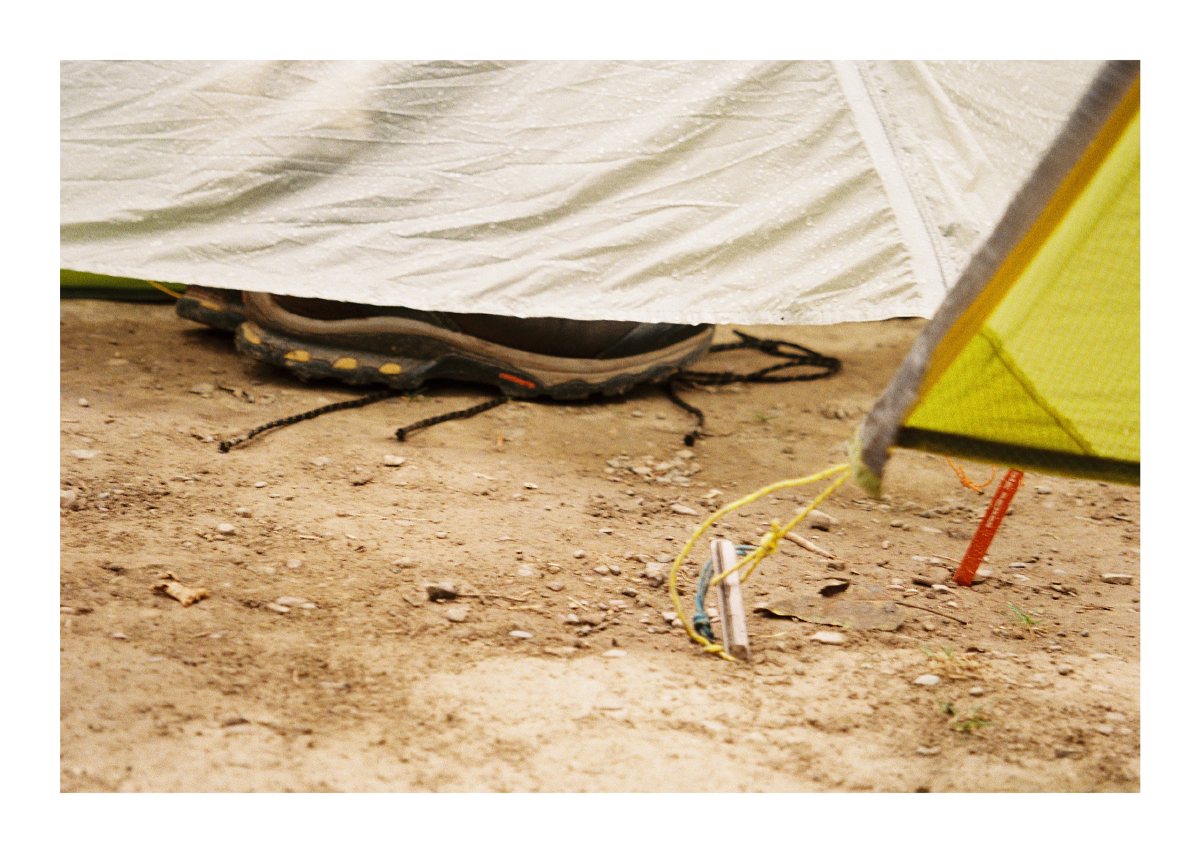 Hiking shoes tucked beneath a rain-spattered tent fly