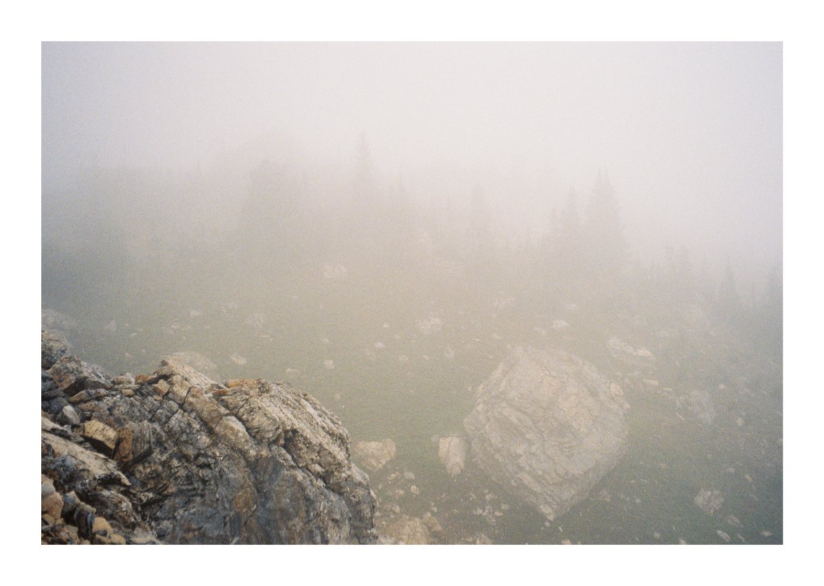 Pale fog obscuring a steep field of broken mountain rock